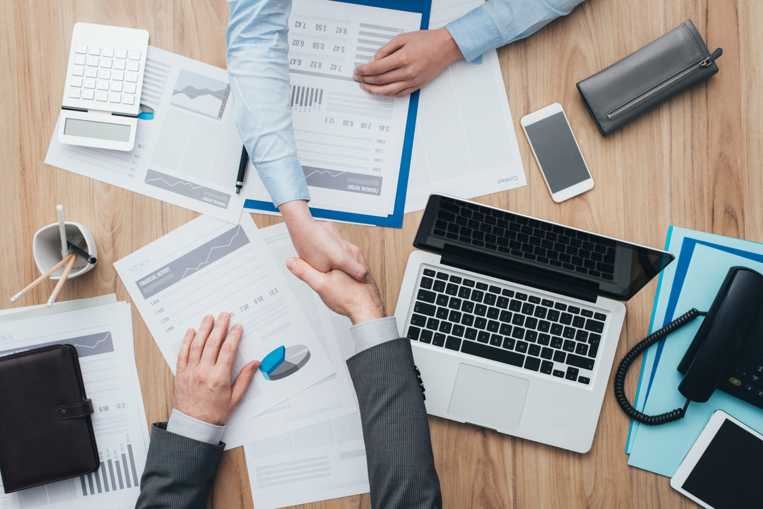 Business people working at office desk and giving an handshake, cooperation and agreement concept